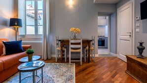 A living room with a sofa, a coffee table, a rug, and a dining area with a table and chairs. - Genteel Home Piazza Pitti II (Florence)