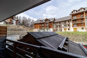 A view of a mountain lodge with multiple wooden balconies and a snowy mountain backdrop.