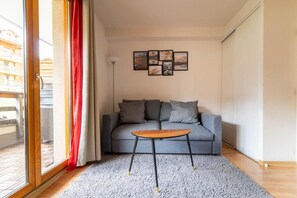 A living room with a grey sofa, a small wooden coffee table, and a grey carpet. - 200m from resort center, 1st floor, swimming pool, balcony, tv, ski locker, 23m², Les Orres (Les Orres)