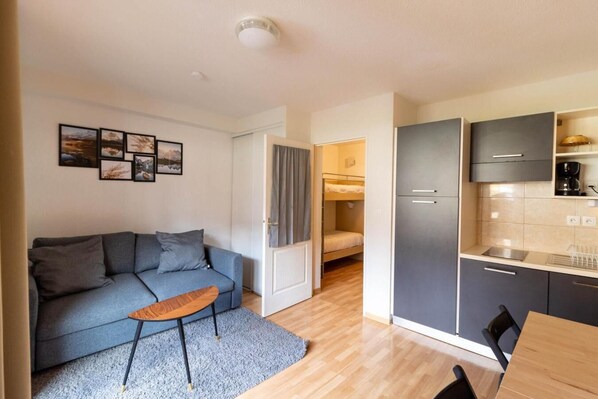 A compact living space with a sofa, a small wooden table, a kitchenette, and a bunk bed. - 200m from resort center, 1st floor, swimming pool, balcony, tv, ski locker, 23m², Les Orres (Les Orres)