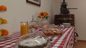 Una mesa de desayuno con diversas opciones de comida, como pasteles, galletas y un vaso de jugo de naranja.