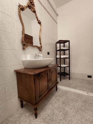 A bathroom with a wooden vanity, a white sink, and a mirror with an ornate frame. - Agriturismo casa alla madonna (San Gimignano)