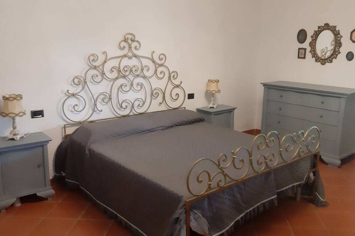 A bedroom with a metal-framed bed, two bedside tables with lamps, a dresser, and wall decorations.