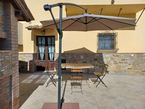 An outdoor patio with a table and chairs, a large umbrella, and a stone wall. - Agriturismo casa alla madonna (San Gimignano)