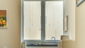 Un pasillo estrecho con una zona de comedor a un lado, una ventana con persianas y un ventilador de techo.