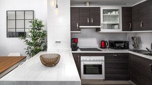 Een moderne keuken met donkerhouten kasten, een inbouwoven, een magnetron en een koffiezetapparaat.