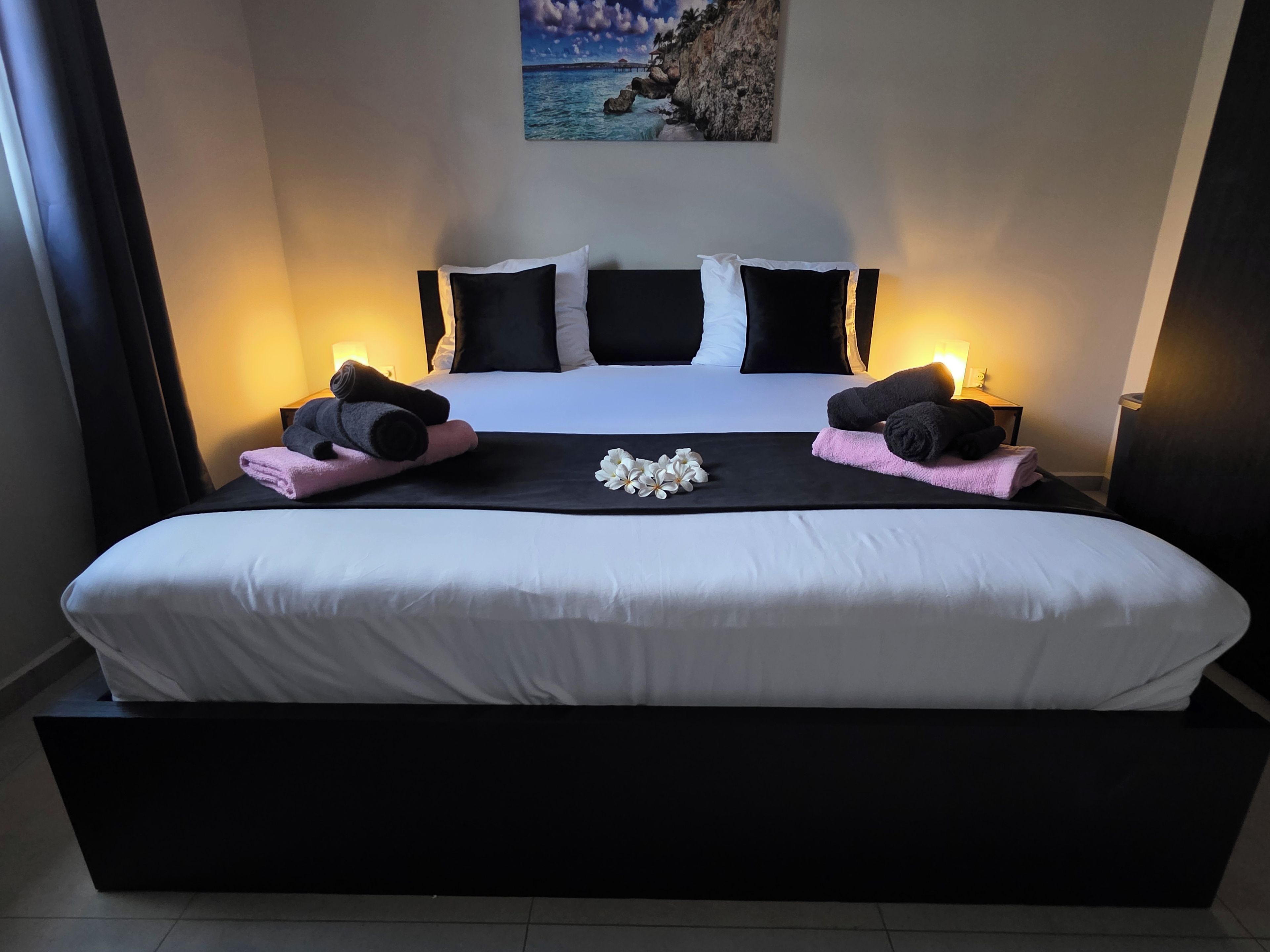A large bed with a black headboard, white bedding, and two side tables with lamps.