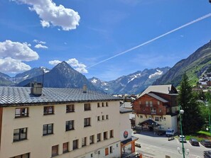 Un paese di montagna con edifici, cielo sereno e montagne innevate sullo sfondo.