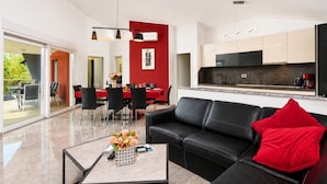 Een moderne woonkamer met een zwarte leren bank, een rode kussens en een salontafel met een bloemenvaas.