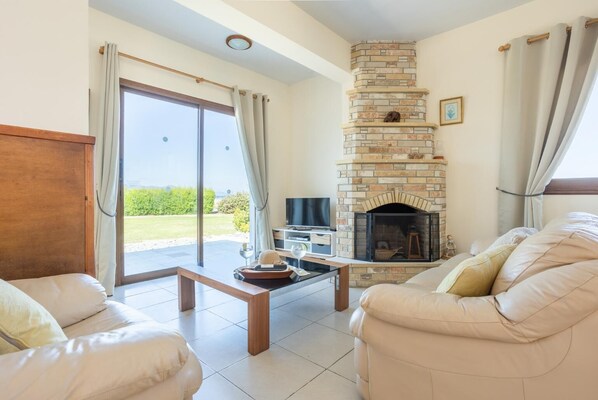 A living room with a fireplace, a sofa, a coffee table, and a TV.