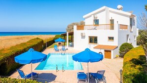 A two-story white building with a pool, blue umbrellas, and a view of the sea. - Blue Bay Villa Thea - Three Bedroom Villa, Sleeps 6 (Polis)