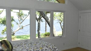 A bedroom with a large window overlooking a body of water and trees. - Modern waterfront home on spacious wooded lot.  Sleeps 6.   (Elberta)