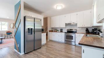 Une cuisine moderne avec des armoires blanches, des appareils en acier inoxydable et un plan de travail en bois.