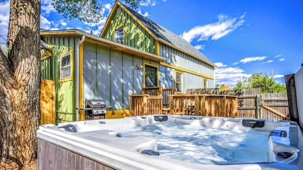 Un bain à remous dans un jardin, avec une terrasse en bois et une maison en arrière-plan.