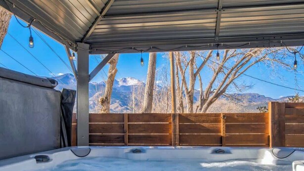 Un espace avec un bain à remous offrant une vue sur les montagnes et les arbres.
