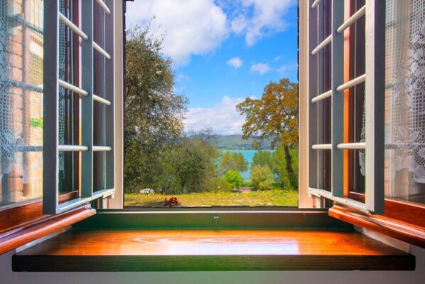 An open window with a view of a lake, trees, and a clear sky.