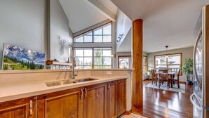 A kitchen with wooden cabinets, a large window, and a dining area with a table and chairs.