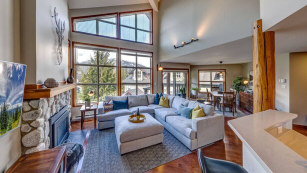 A spacious living room with a large sectional sofa, a fireplace, and a dining area with a table and chairs.