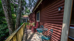 A wooden deck with a table and chairs, surrounded by trees. - Queen Bedroom with Loft (Blowing Rock)