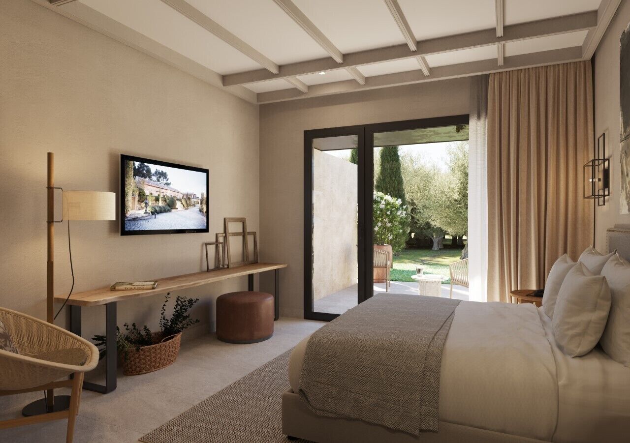 Un dormitori modern amb un llit gran, escriptori, televisió i vista a un jardí a través d'una porta corredissa de vidre.