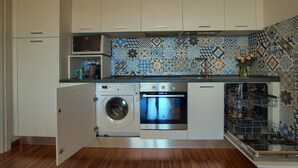 A compact kitchen with a washing machine, oven, and dishwasher built into the cabinetry. - Two Bedroom Apartment with Pool, Jacuzzi, A/C, WiFi and Electric Bicycles (Bordighera)