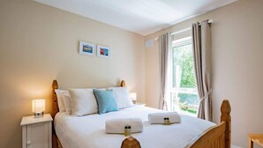 Ein ordentlich eingerichtetes Schlafzimmer mit einem hölzernen Bett, weißer Bettwäsche und zwei Nachttischlampen.