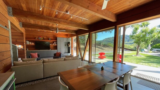 A modern interior with a wooden ceiling, a dining area with a table and chairs, a sofa, and a kitchen area with cabinets and a TV. - Modern Retreat 15 minutes from Healdsburg Square (Healdsburg)