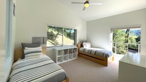 A bedroom with two beds, a ceiling fan, a window with a view of trees, and a white bookshelf. - Modern Retreat 15 minutes from Healdsburg Square (Healdsburg)
