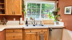 A kitchen with wooden cabinets, a stainless steel sink, a dish rack, and a dishwasher.