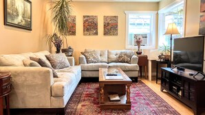 A living room with a sofa set, a coffee table, a TV, and artwork on the walls.