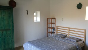 Une chambre à coucher avec un lit, une tête de lit en bois, une table de chevet, une étagère et une armoire verte.