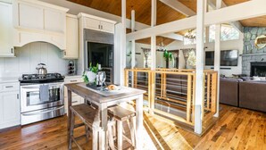 Une cuisine avec des poutres en bois, une cheminée en pierre et un coin repas comprenant une table et des chaises en bois.