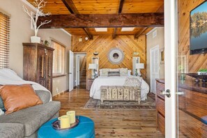 Ein Schlafzimmer mit Holzboden, einem Bett, einem Schrank und einem Fernseher.