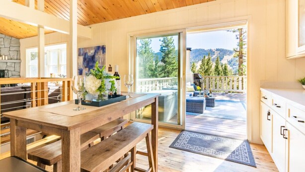 Un intérieur en bois comprenant un coin repas, une cuisine et donnant sur une terrasse extérieure.