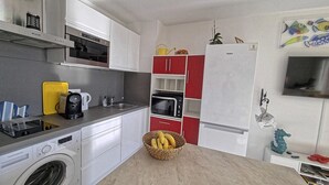 Cocina compacta con lavadora, cafetera y microondas.