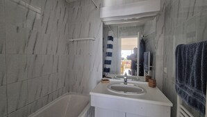 Un baño con bañera, lavamanos y espejo.
