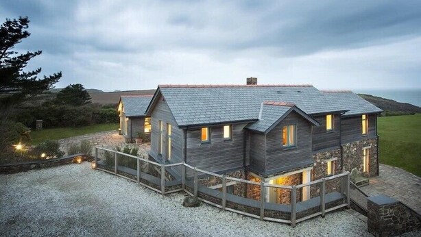 A modern house with a sloped roof, multiple windows, and a stone foundation.