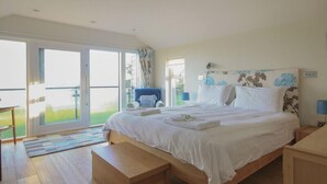 A spacious bedroom with a large bed, a chair, and a view of the outdoors through a sliding glass door.