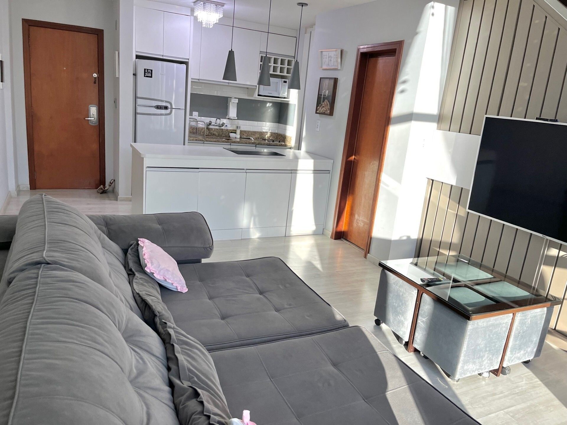 Una sala de estar moderna con un sofá gris, una mesita y un televisor.