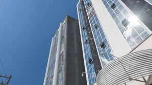 Een hoog gebouw met een moderne glazen gevel en een cilindervormige structuur aan de basis.