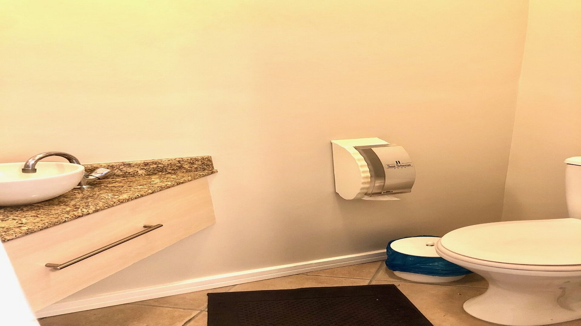 A bathroom with a sink, toilet, and paper towel dispenser.