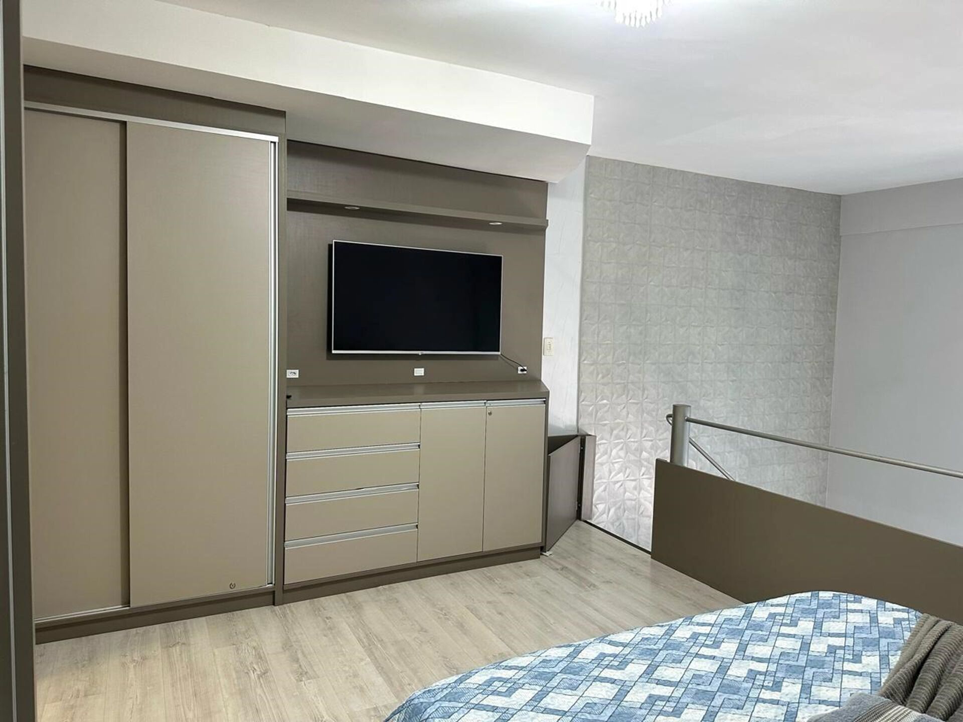 A bedroom with a bed, a TV mounted on a cabinet, and a wardrobe.