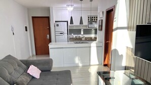 Een moderne woonkamer met een grijze bank, een glazen salontafel en een tv-meubel.