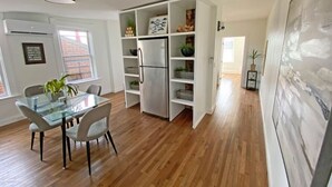 A modern kitchen with a glass dining table, white cabinetry, and a stainless steel refrigerator. - Explore Downtown and Mount Adams with River Views! (Cincinnati)