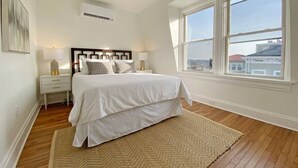 A bedroom with a bed, bedside tables, a rug, and a large window with a view. - Explore Downtown and Mount Adams with River Views! (Cincinnati)