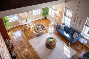 A spacious living room with a blue sofa, a round coffee table, and a dining area with a white table and chairs.