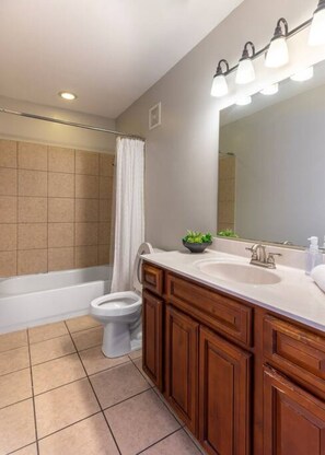 A modern bathroom with a bathtub, toilet, and vanity with a mirror and sink.