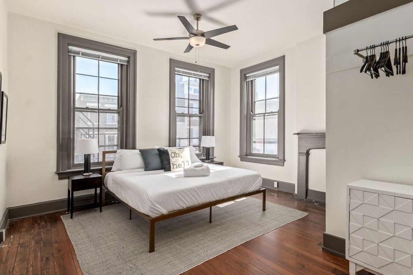 A bedroom with a bed, nightstands, a ceiling fan, and a fireplace.