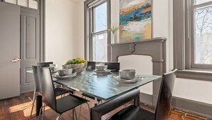 Un coin repas avec une table dressée pour quatre personnes, une cheminée et une grande fenêtre donnant sur l’extérieur.