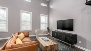 A modern living room with a leather sofa, a coffee table, a TV, and a console table. - Soaring 2-Bedroom Parkside Loft Walkable to it All (Cincinnati)